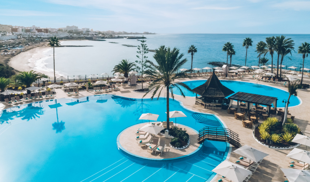 Hotelzwembad met uitzicht op zee op Tenerife en palmbomen overal.