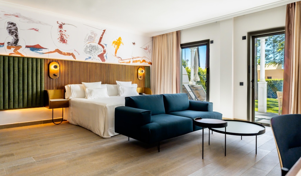 Moderne kamer op Tenerife met een tweepersoonsbed, bank, tafels en balkon met uitzicht op de tuin.