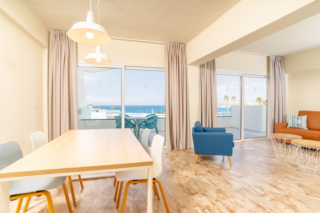 Woonkamer met zeezicht op Tenerife, met eettafel en fauteuils.