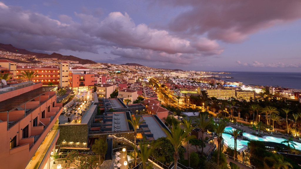 Nachtelijk uitzicht op de kust van Tenerife met verlichte gebouwen en de zee op de achtergrond.