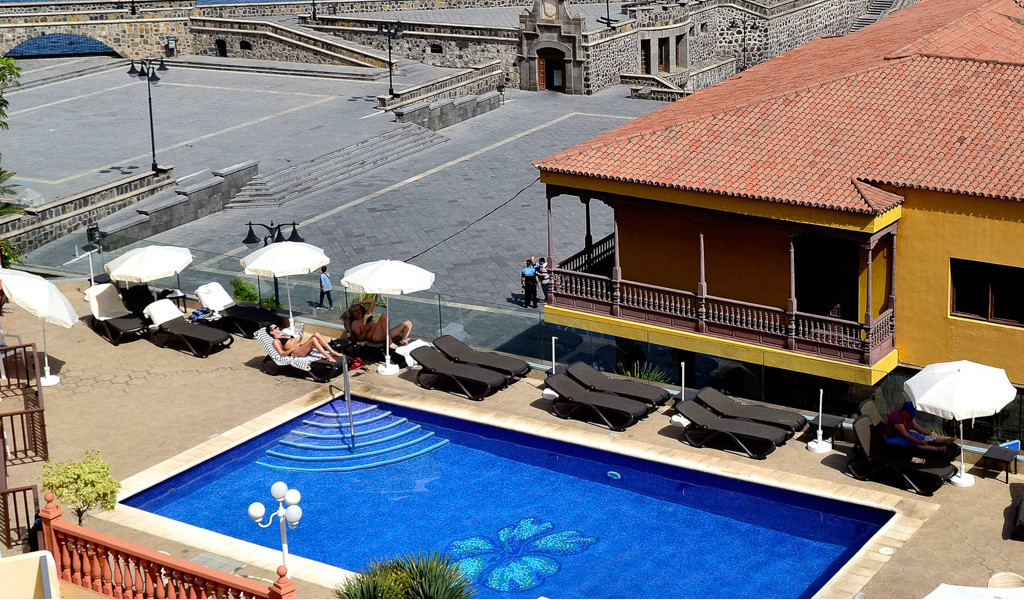Buitenzwembad met parasols en ligstoelen op een plein op Tenerife.