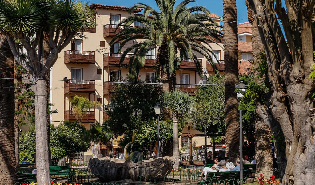 Met bomen omzoomd plein met gebouwen en mensen die rusten in Puerto de la Cruz, Tenerife.