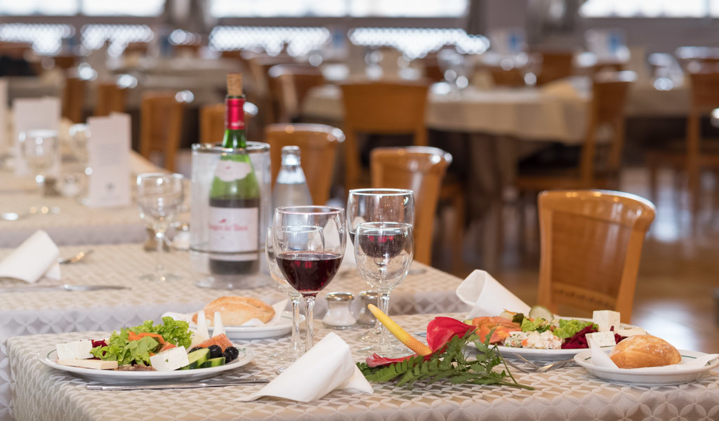 Tafel geserveerd met salades, brood, glazen rode wijn en een fles in een restaurant op Tenerife.
