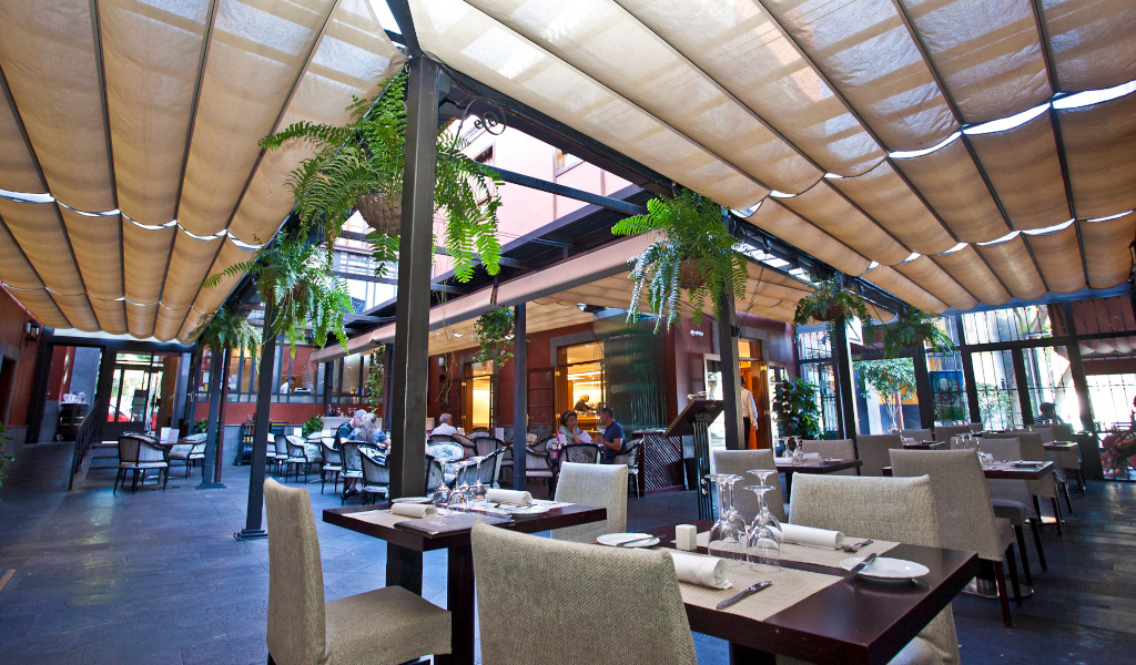 Openluchtrestaurant op Tenerife met tafels en hangende planten.
