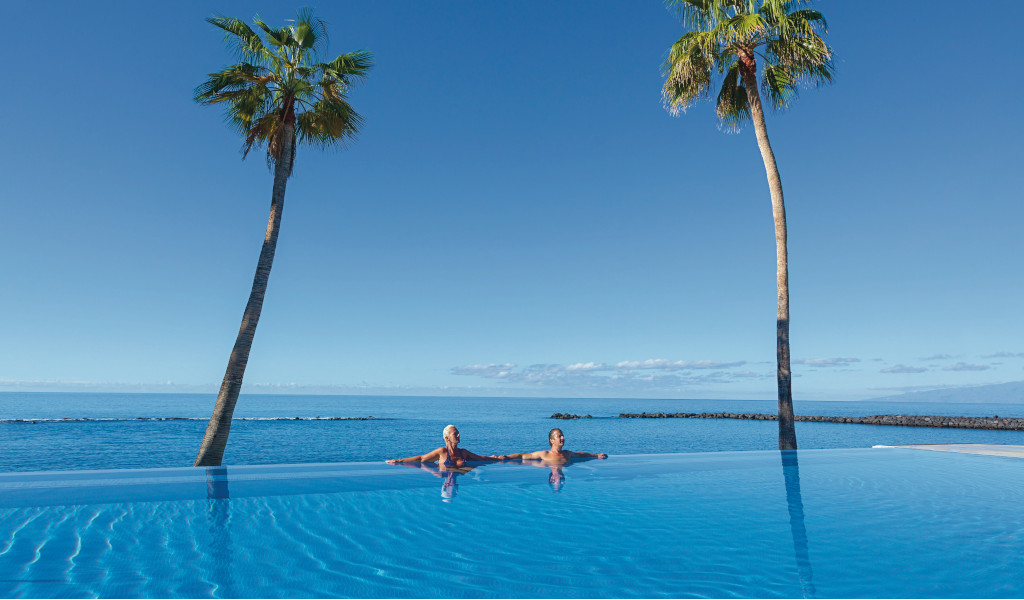 Iemand die geniet van een infinity pool met uitzicht op de oceaan op Tenerife.