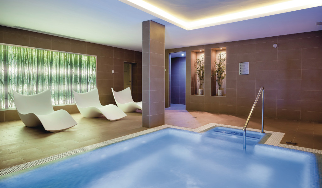 Binnenzwembad en loungegebied met witte stoelen in de spa van Tenerife.