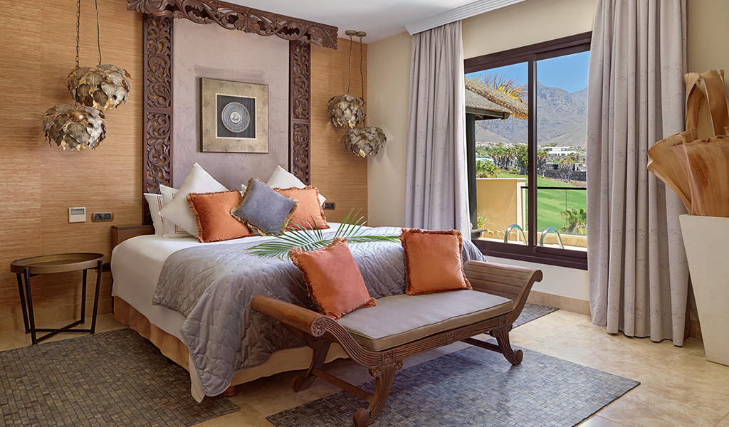 Kamer met bed, oranje kussens, raam met landschapsuitzicht in Adeje, Tenerife.