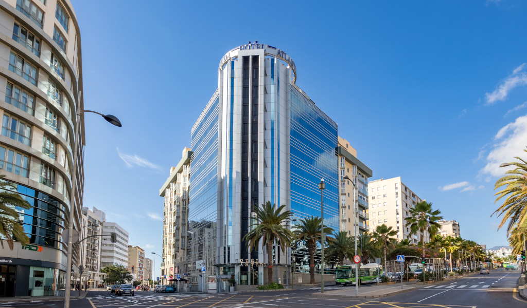 Moderne gebouwen en palmbomen aan een straat in Santa Cruz de Tenerife onder een blauwe lucht.