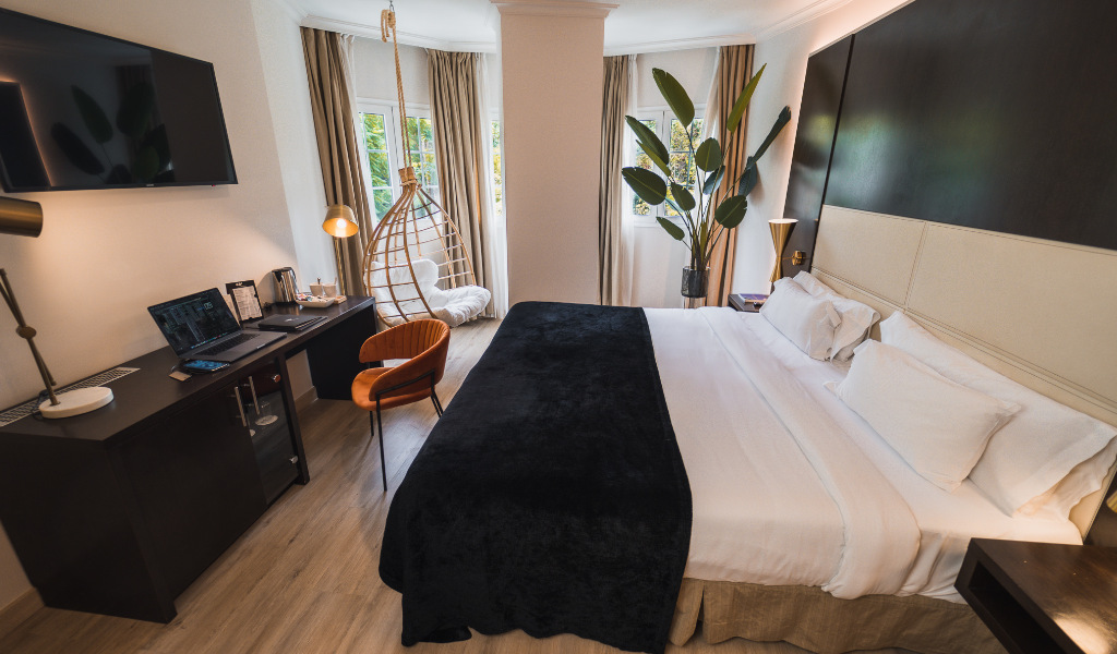 Moderne kamer met een groot bed, bureau met laptop en hangstoel op Tenerife.