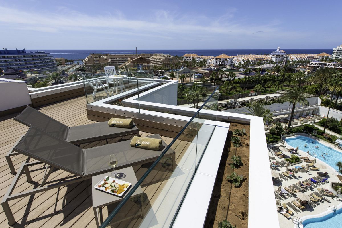 Terras met ligstoelen, uitzicht op zee en zwembad in een hotel op Tenerife.