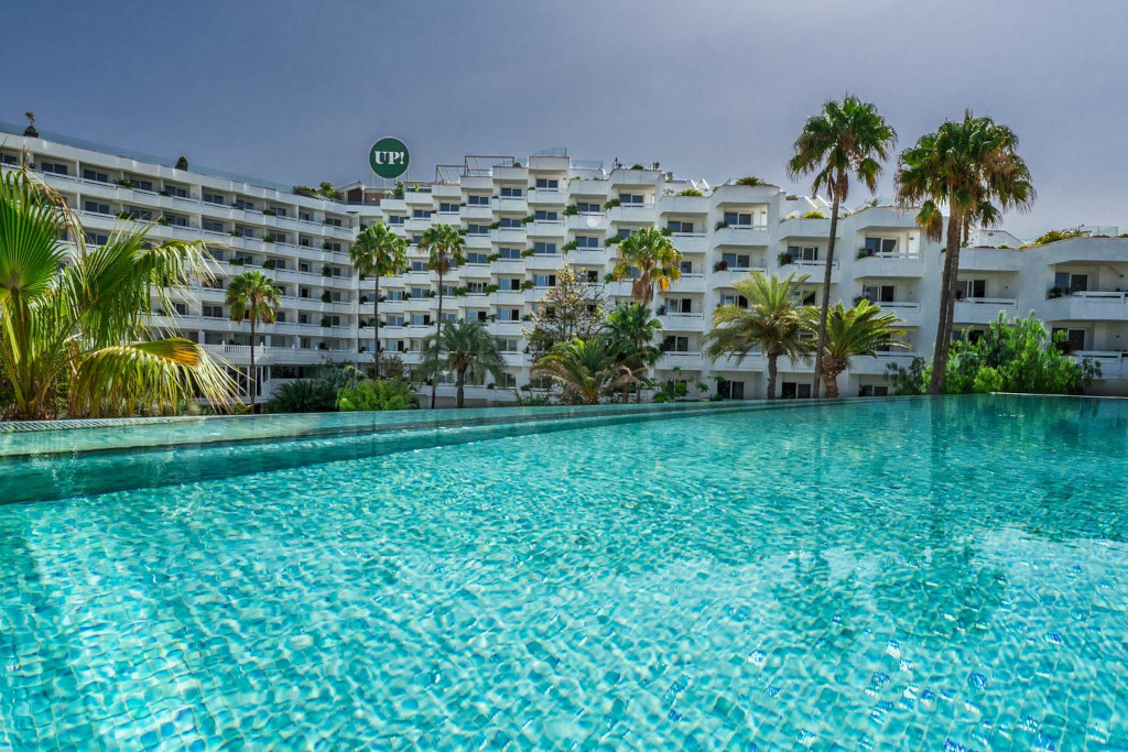 Zwembad voor een gebouw omringd door palmbomen op Tenerife.
