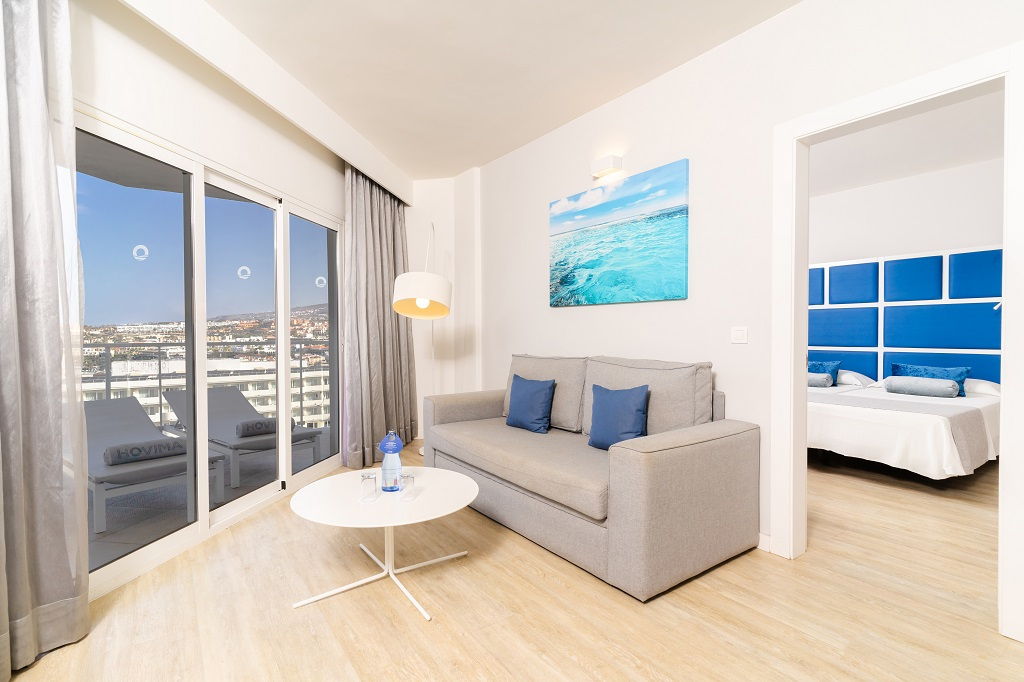 Lichte woonkamer met een grijze bank en uitzicht op de stad op Tenerife.