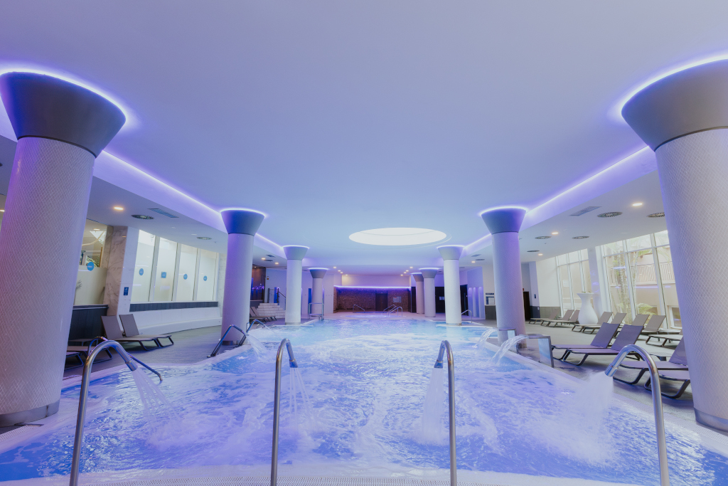 Binnenzwembad met waterstralen en ligstoelen in een spa op Tenerife.