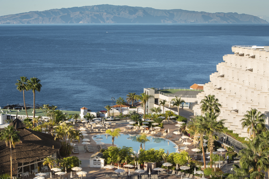 Zwembad en palmbomen met uitzicht op de oceaan in een hotel op Tenerife.