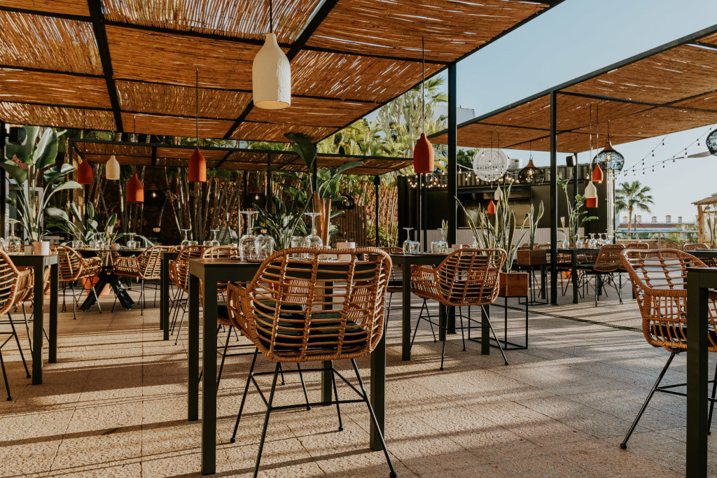 Buitenterras van restaurants op Tenerife met rieten stoelen en planten.