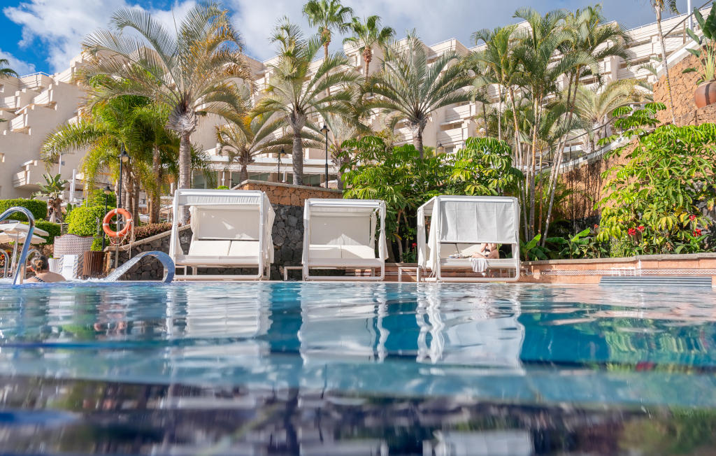Zwembad en Balinese bedden omringd door palmbomen in een hotel op Tenerife.