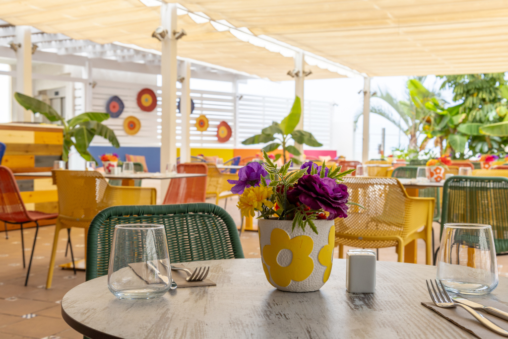 Tafel met bloemen en kleurrijke stoelen in een openluchtrestaurant op Tenerife.