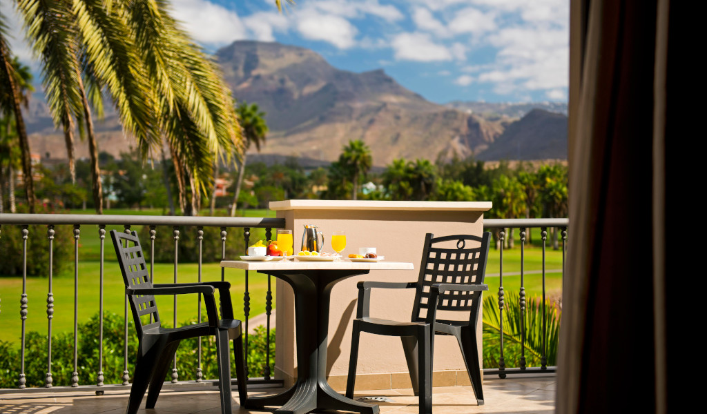 Ontbijt op een terras met uitzicht op bergen en palmbomen op Tenerife.