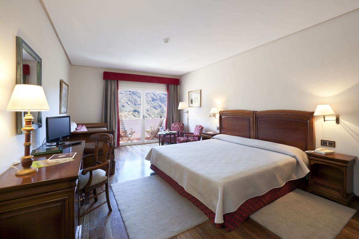 Hotelkamer met tweepersoonsbed, tv en balkon met uitzicht op de bergen op Tenerife.