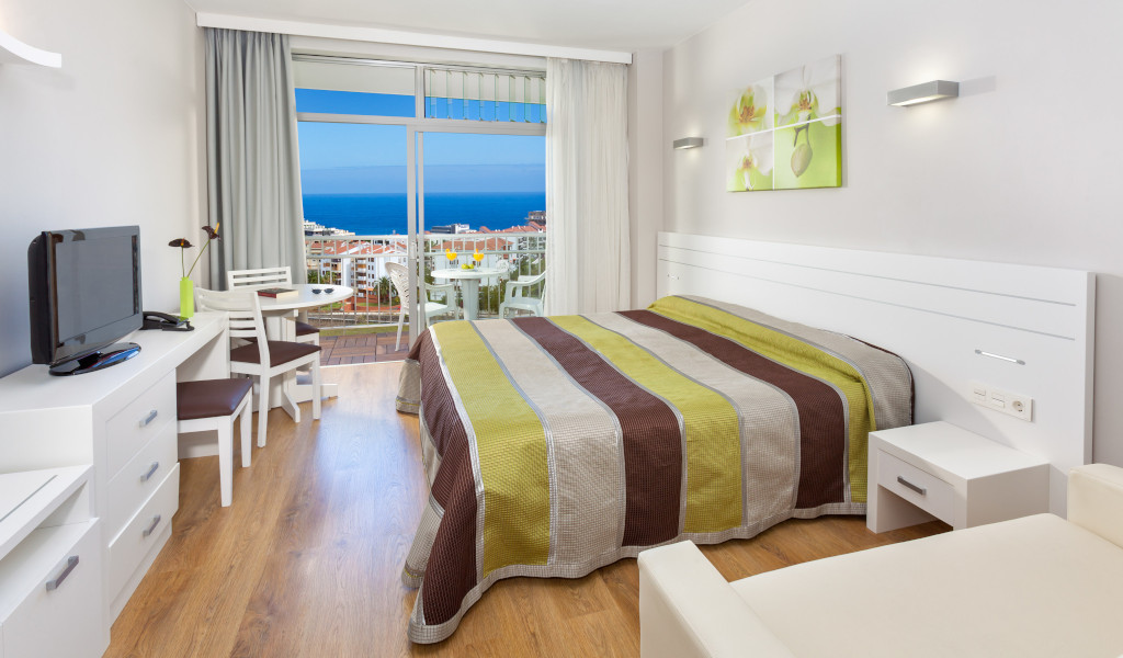 Kamer met tweepersoonsbed, ronde tafel, tv en zeezicht op Tenerife.