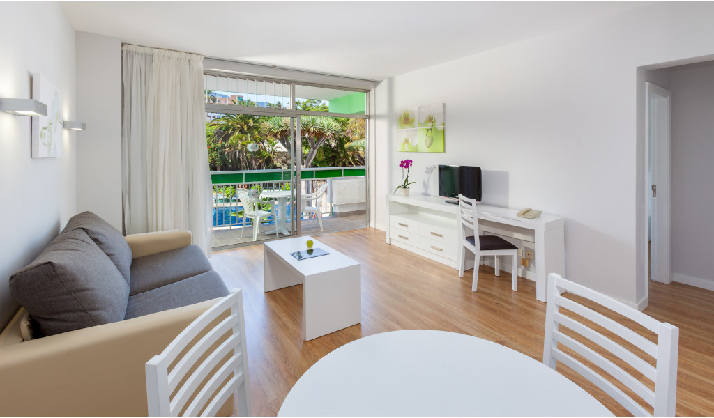 Woonkamer met bank, tafel en tv, uitzicht op de tuin op Tenerife.
