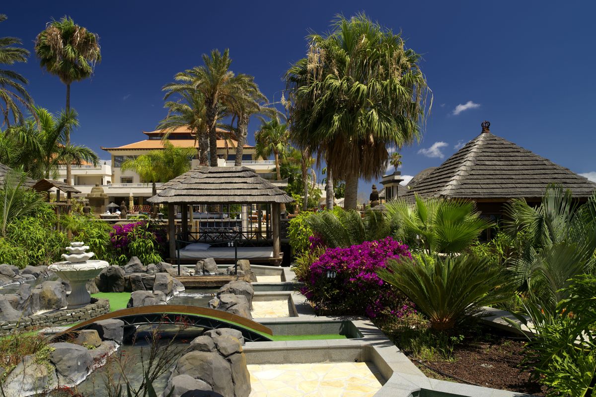 Tuinen met palmbomen en houten hutten in een hotel op Tenerife.
