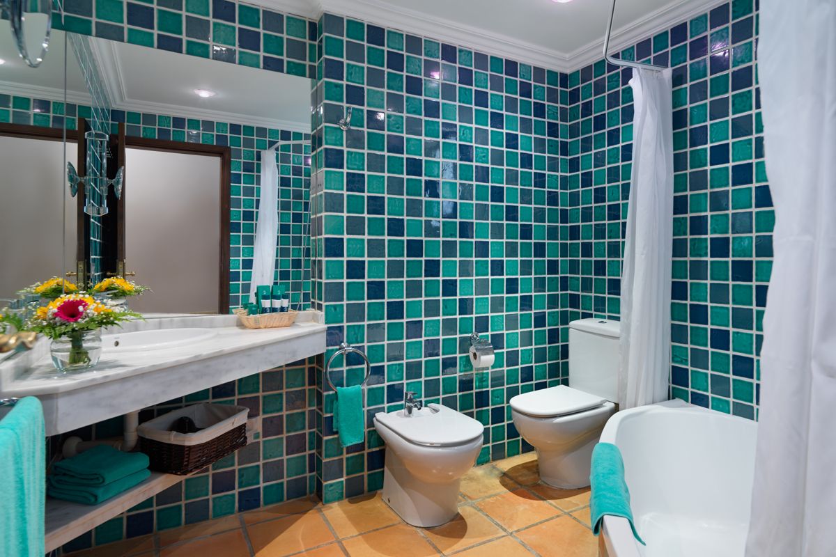 Badkamer met blauwe tegels, wastafel, bidet en bloemen op Tenerife.