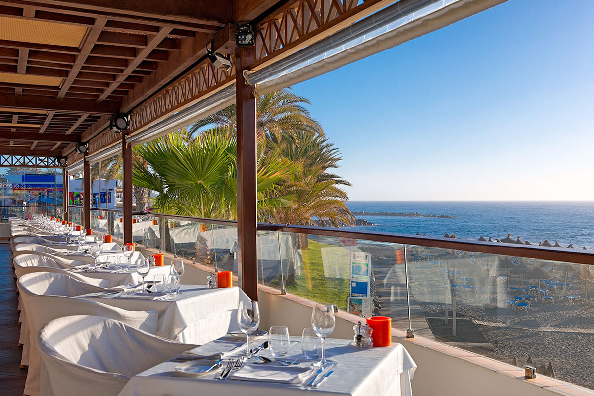 Restaurantterras met uitzicht op zee op Tenerife, tafels klaargemaakt voor eters.