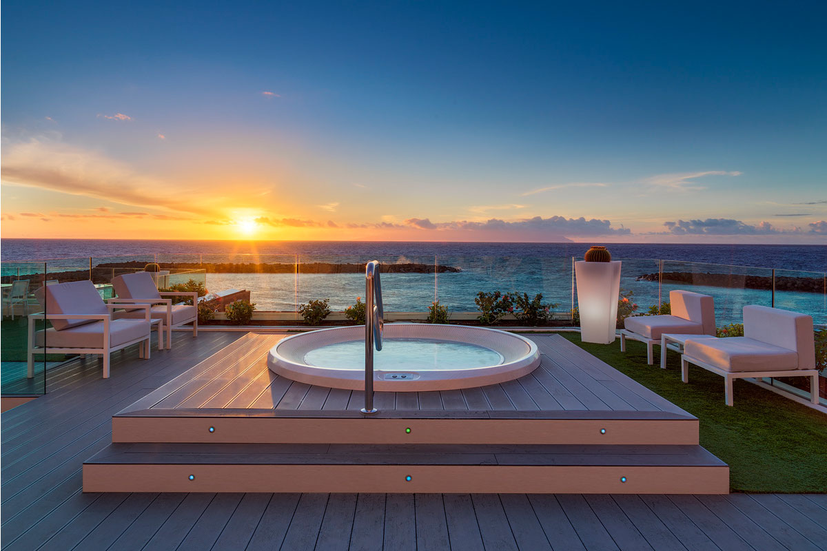 Zonsondergang over zee vanaf een terras met jacuzzi en stoelen op Tenerife.