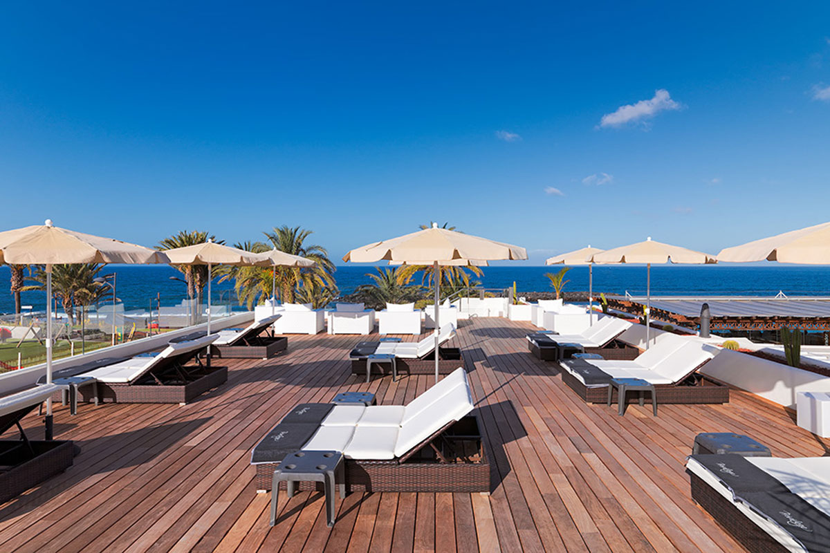 Terras met ligstoelen en parasols met uitzicht op zee in Santa Cruz de Tenerife.
