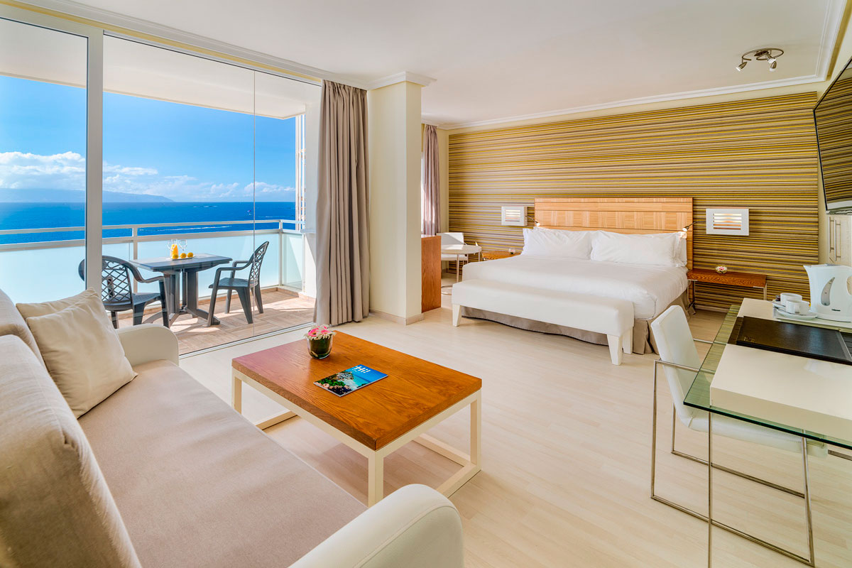 Een lichte kamer met een groot bed en een balkon met uitzicht op zee op Tenerife.