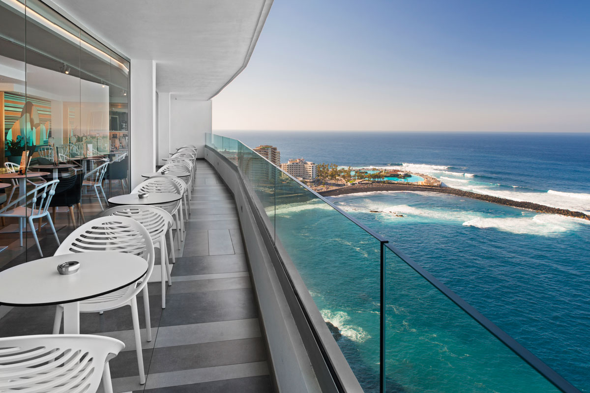Terras met uitzicht op de oceaan in Puerto de la Cruz, Tenerife. Tafels en stoelen stonden op een rij.