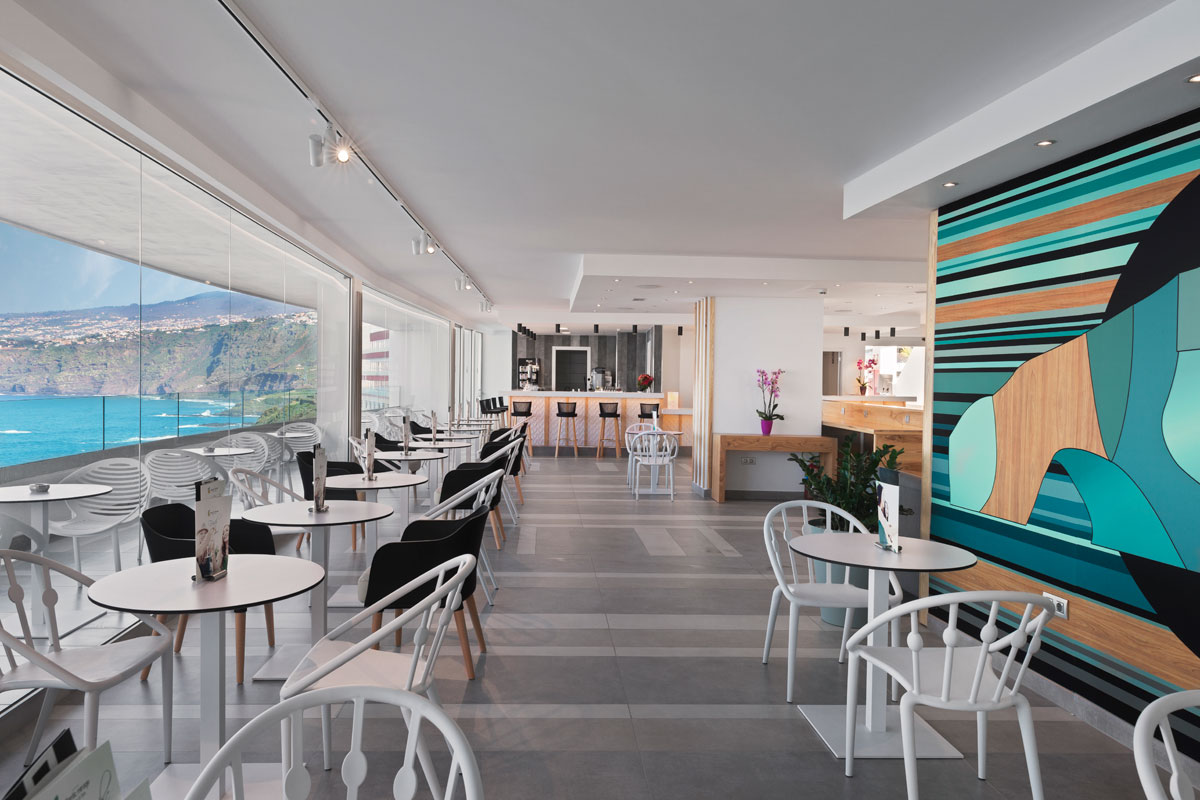 Interieur van een modern café met zeezicht op Tenerife, witte tafels en stoelen.
