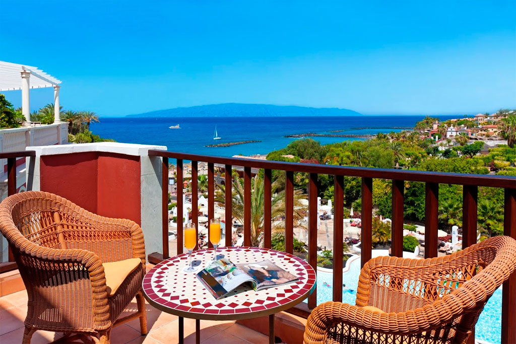 Zeezicht vanaf een balkon met stoelen en tafel op Tenerife.