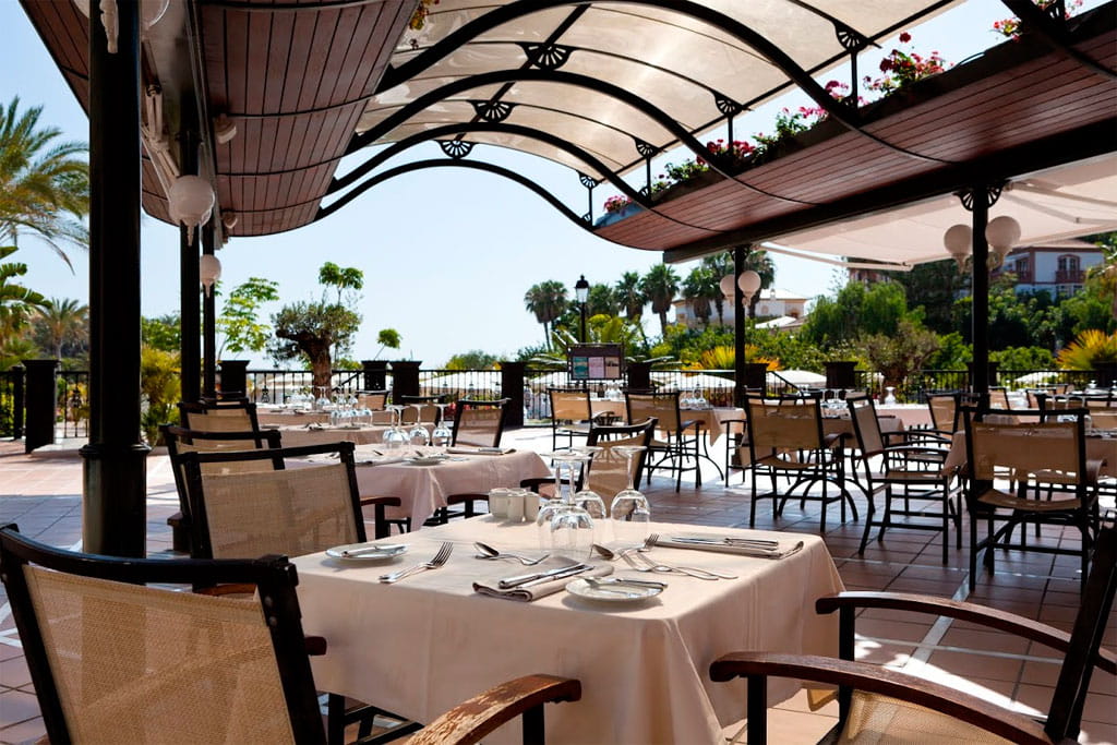 Restaurantterras op Tenerife met voorbereide tafels en uitzicht op de tuin.