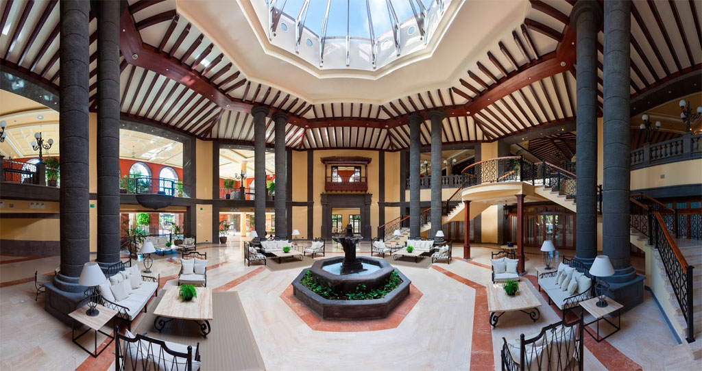 Hotellobby met glazen dak op Tenerife, elegante inrichting en hoge zuilen.