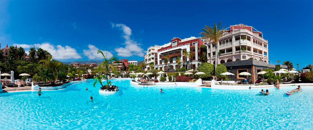 Zwembad in een luxe hotel op Tenerife met volwassenen en kinderen die zwemmen.