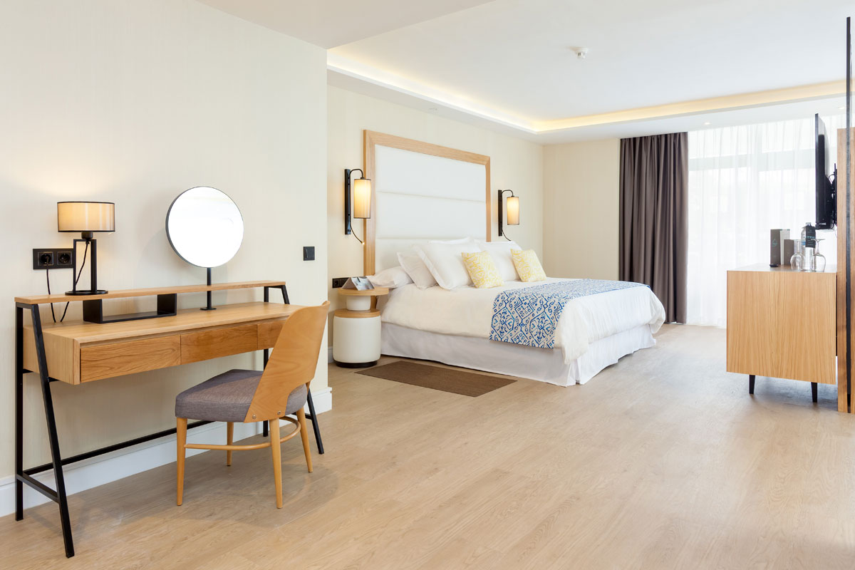 Moderne hotelkamer op Tenerife met een groot bed en een houten bureau.
