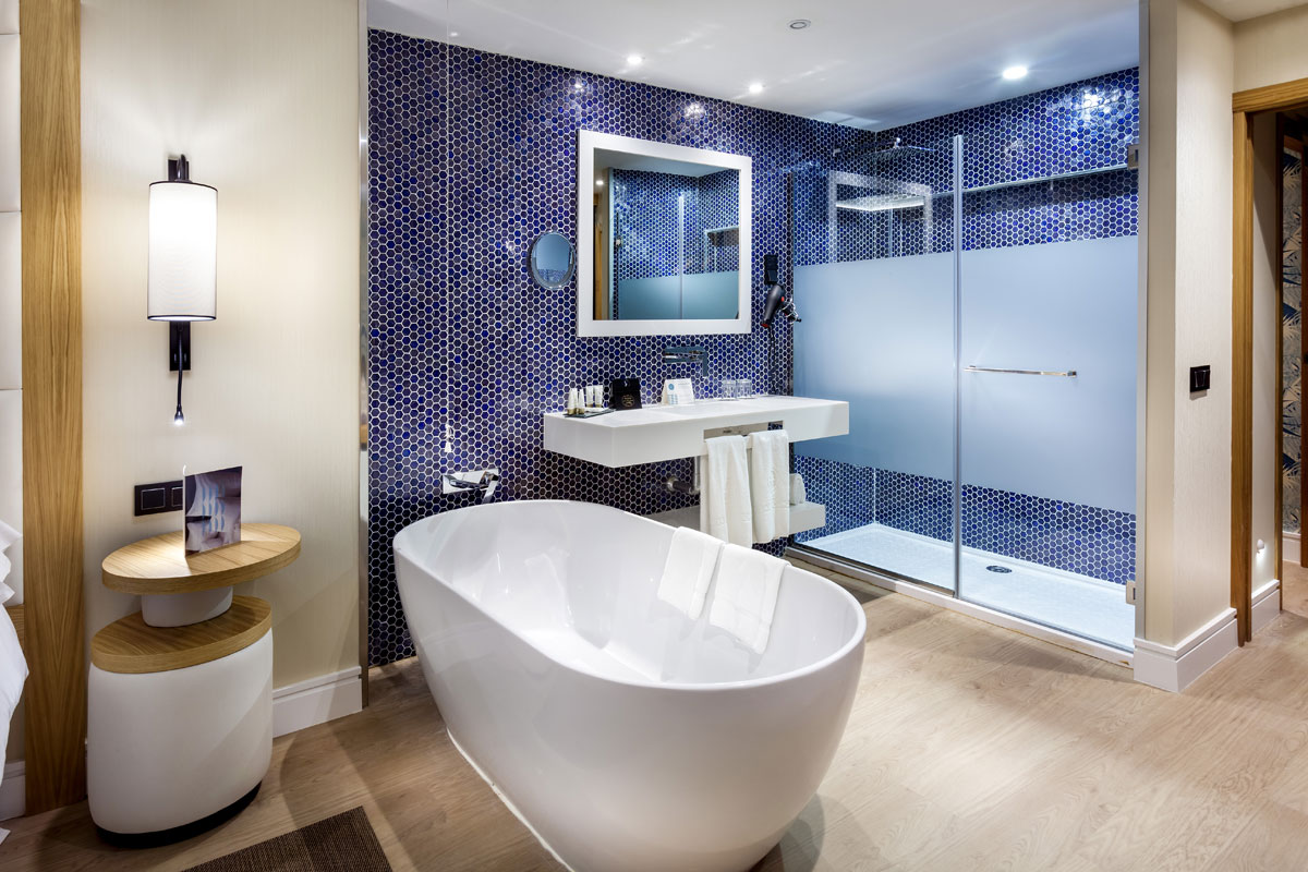 Moderne badkamer met wit bad en douche, blauwe tegels op Tenerife.