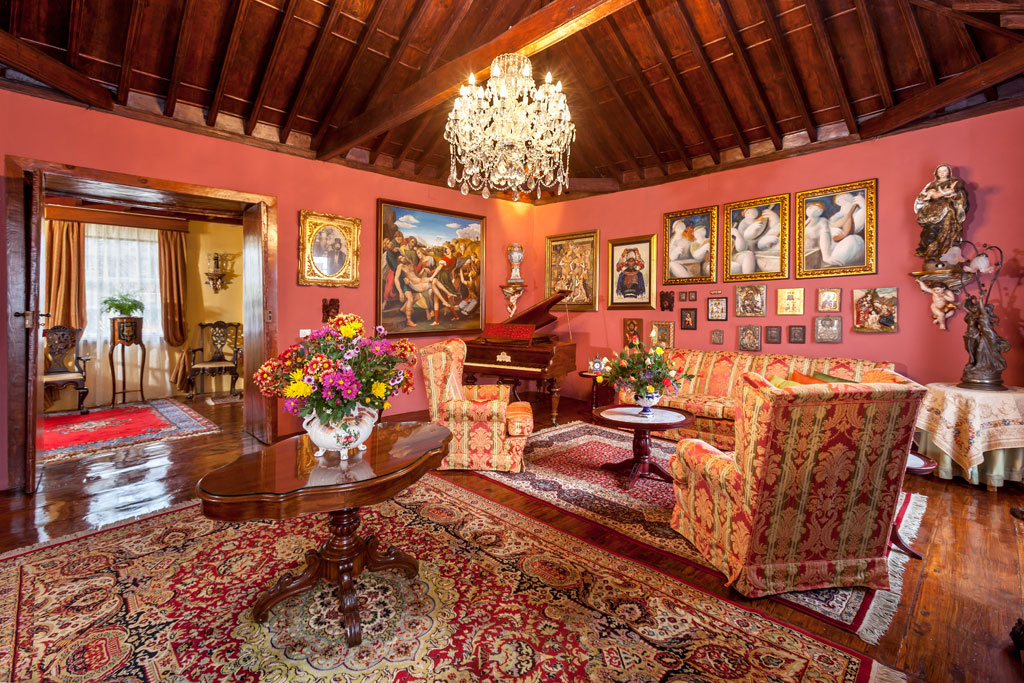 Elegante woonkamer met banken, piano, bloemen en schilderijen in Tenerife.