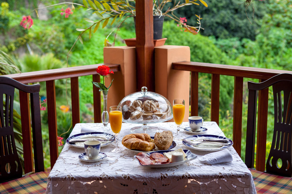 Ontbijt met sap en brood op een terras met uitzicht op de tropische tuin op Tenerife.