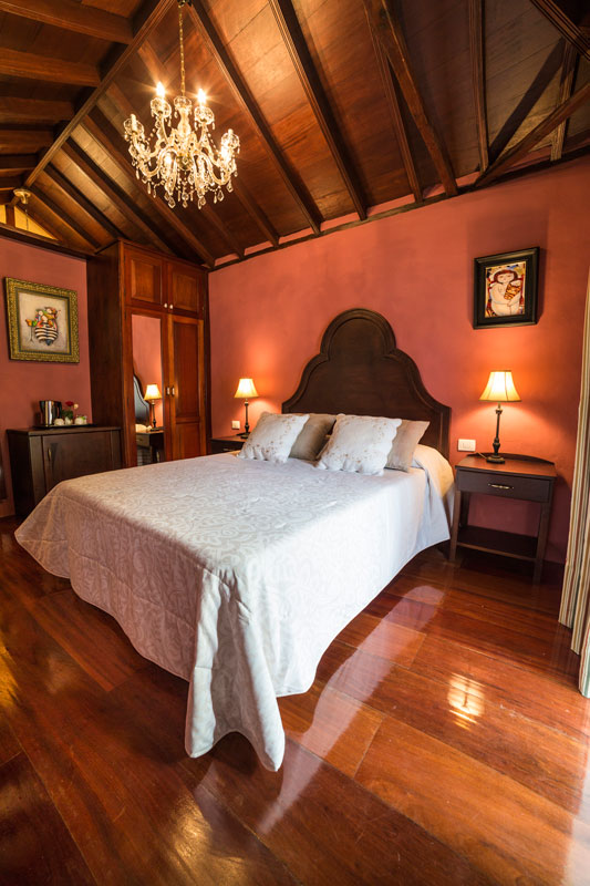 Kamer met tweepersoonsbed, houten plafond en kroonluchter op Tenerife.