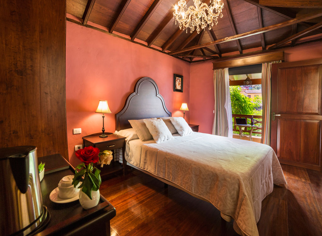 Kamer met tweepersoonsbed, lampen en uitzicht op de tuin in een accommodatie op Tenerife.