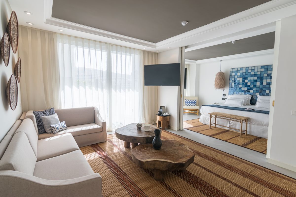 Woonkamer met beige bank en een bed met een eigen badkamer en blauw mozaïek op Tenerife.