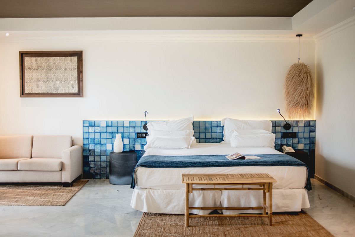 Hotelkamer op Tenerife met bed, witte kussens en blauwe decoratie.