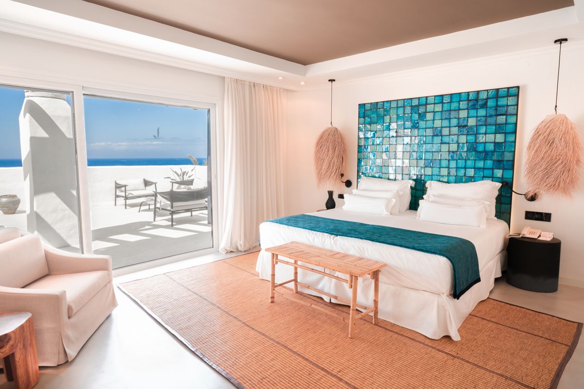 Kamer met bed, blauwe decoratie en terras met zeezicht op Tenerife.
