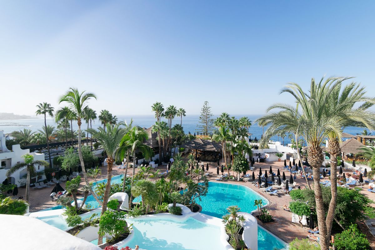 Zwembad met palmbomen en uitzicht op de oceaan in een hotel op Tenerife.