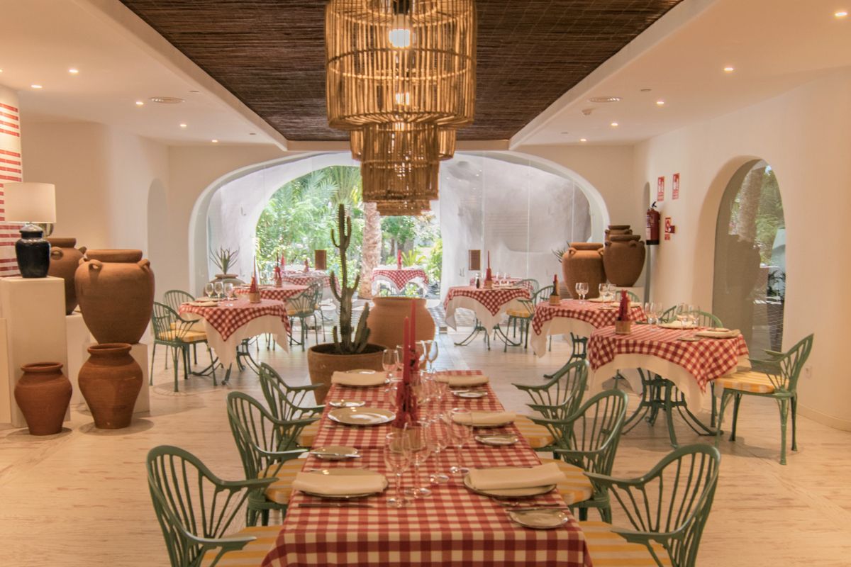 Restaurant met rood geruite tafelkleden op Tenerife, vaasdecoratie en hanglampen.