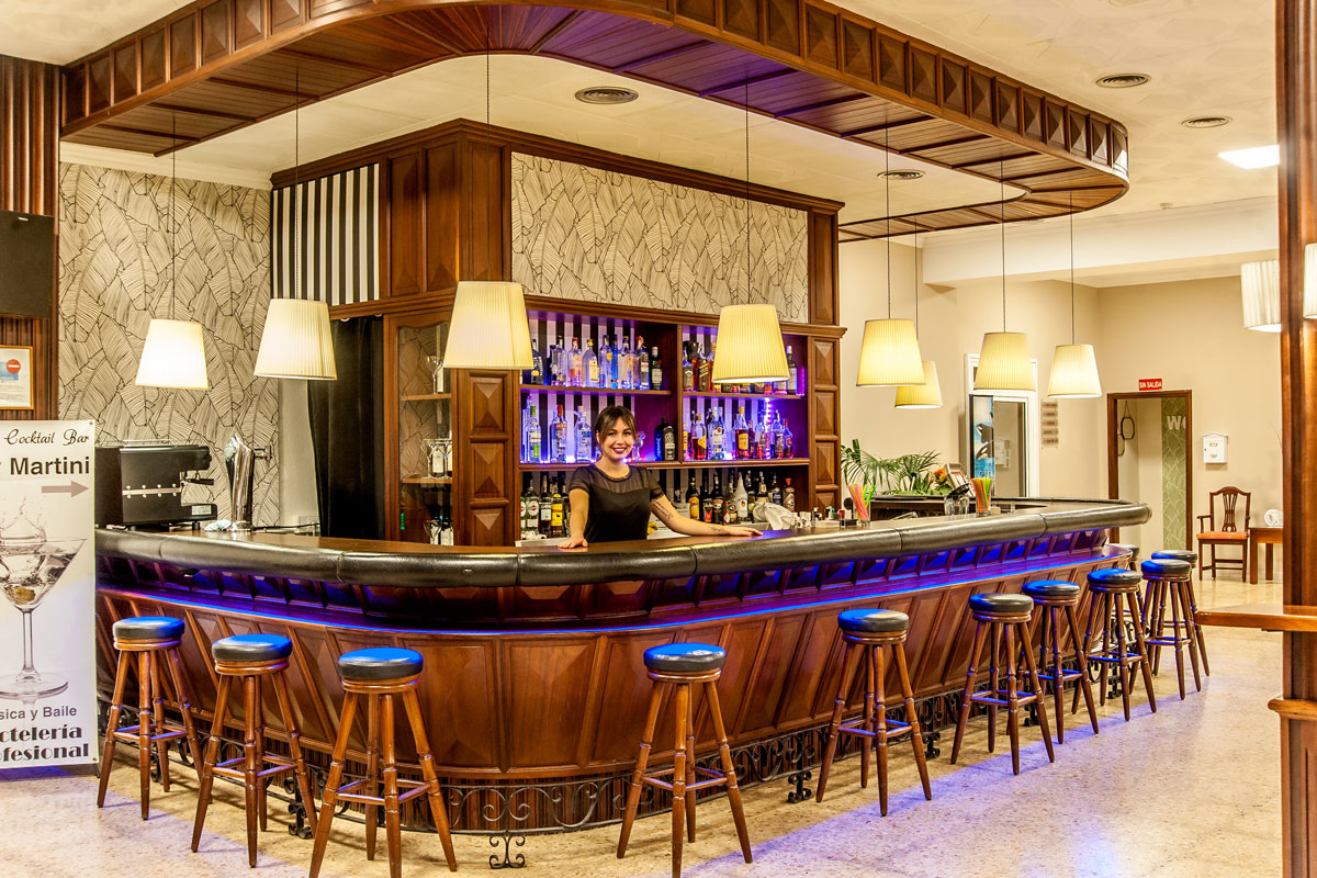 Persoon die de bar bedient met drankrekken en krukken op Tenerife. Kartelpunten, Martini.
