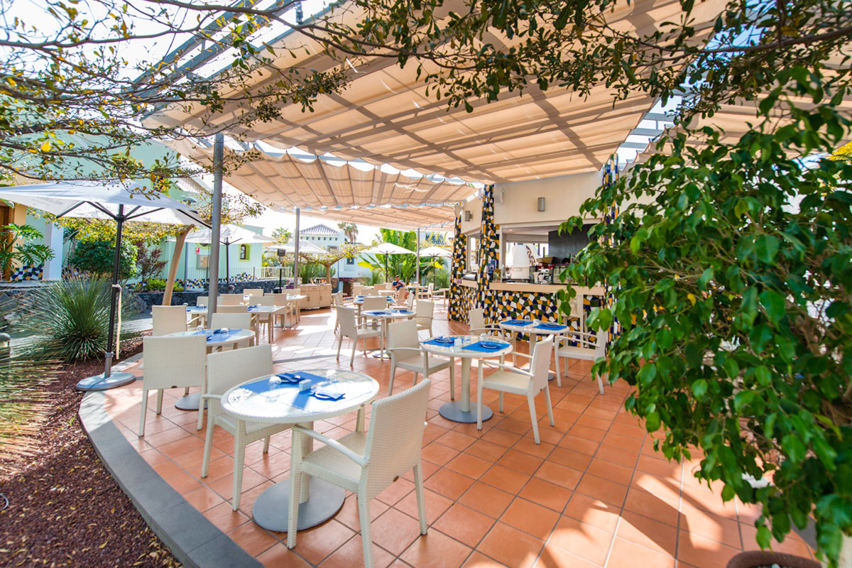 Terras van een restaurant op Tenerife met witte tafels en stoelen onder een luifel.